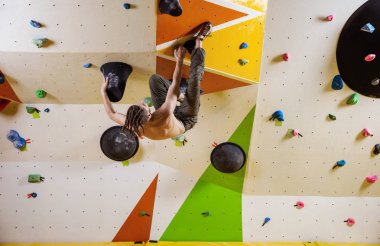 Genç adam zorlu bouldering rota. Tırmanma kapalı spor salonunda.
