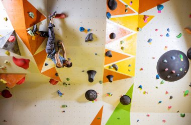 Genç kaslı adam zorlu bouldering rota tırmanma. Tırmanma kapalı spor salonunda
