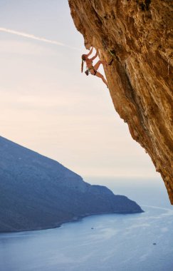 Genç kadın dağcı cliff üzerinde zorlu yolu üzerinde. Kalimnos Adası, Yunanistan.