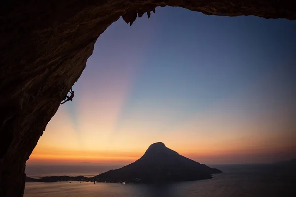 背景の島の美しい景色と夕焼けに張り出した崖の上男性ロック クライマー カリムノス島 ギリシャ — ストック写真