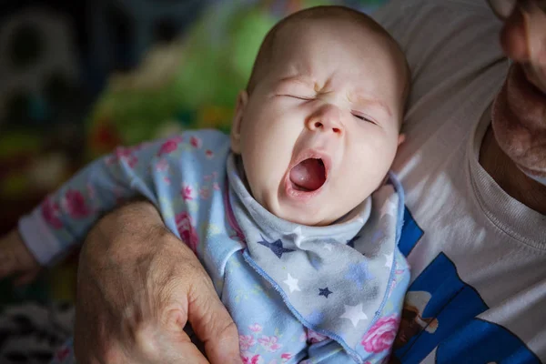 Девочка зевает. Дедушка качает ребенка спать . — стоковое фото