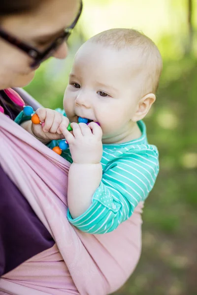 Young woman carrying her baby daughter in woven wrap outdoors — Stock Photo, Image