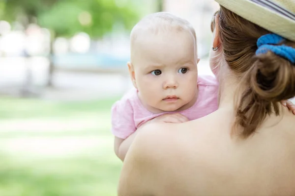 Baby girl looking over mother's shoulder with caution — Stock Photo, Image