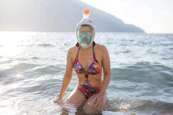 Ung kvinna i mask för snorkling som sitter i grunt vatten — Stockfoto