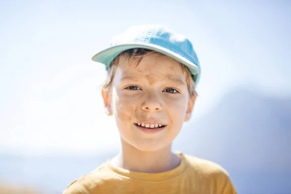Ung pojke med med smutsiga fläckar i ansiktet efter att ha spelat utomhus — Stockfoto