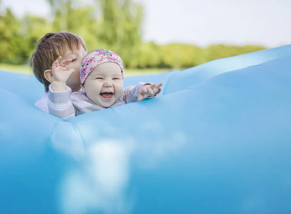 Hermanos jugando en sofá inflable al aire libre —  Fotos de Stock