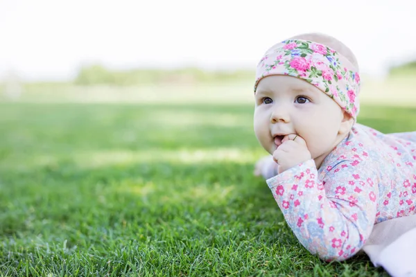 Bonito bebê menina olhando para cima enquanto deitado na grama no parque — Fotografia de Stock