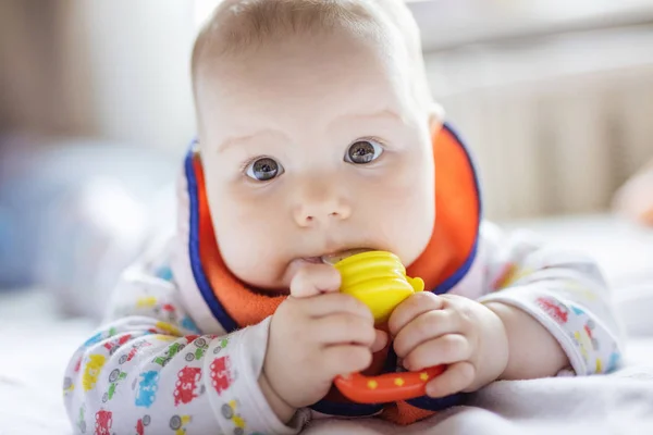 Lindo bebé comiendo fruta en mordisquear en la cama en casa —  Fotos de Stock