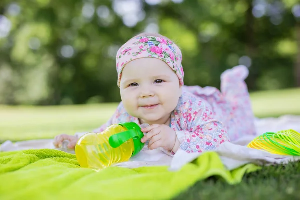 Cute baby girl with bottle of water in summer park — Stock Photo, Image