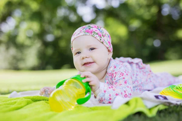 Niña alegre con biberón de agua en el parque de verano —  Fotos de Stock