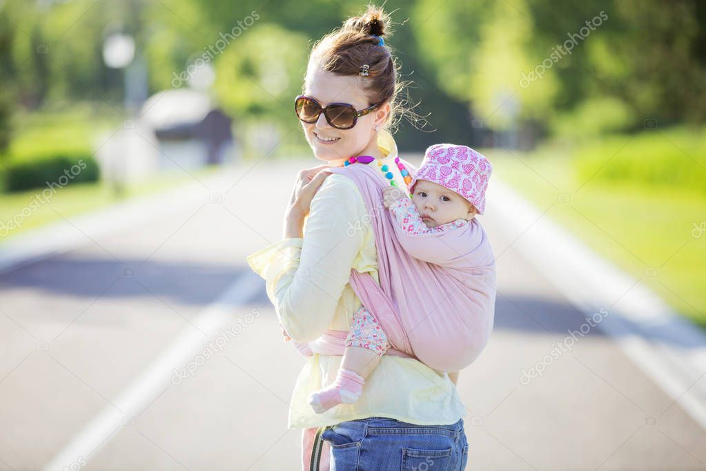 Cheerful Caucasian woman carrying her baby daughter on back 