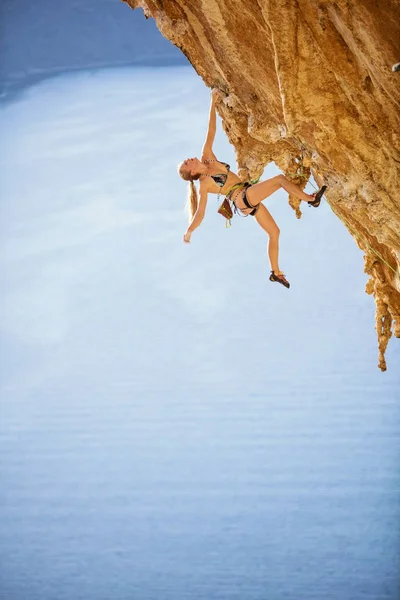 Młoda kobieta wspinacz Rock w bikini wiszące z jednej strony — Zdjęcie stockowe