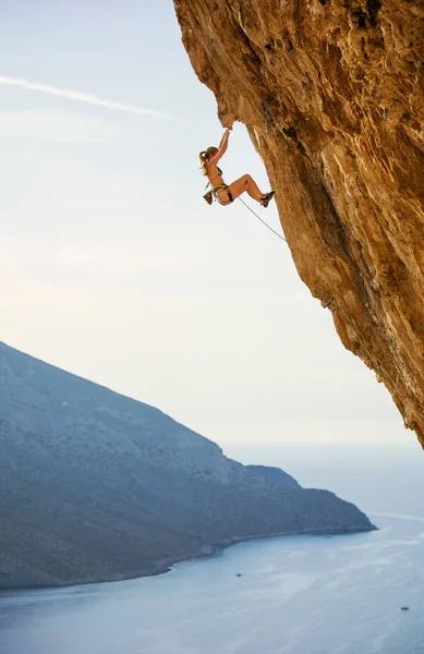 Jeune femme en bikini escalade route difficile sur falaise surplombant — Photo