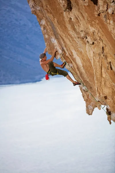 Молодой человек поднимается по сложному маршруту на нависшей скале — стоковое фото