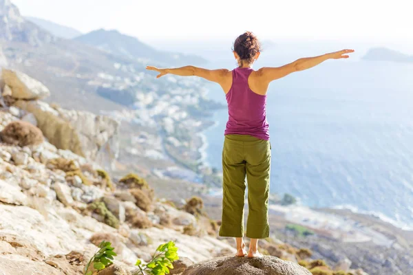 Joven mujer caucásica practicando yoga mientras está de pie en el acantilado — Foto de Stock