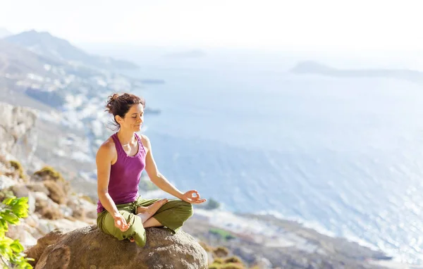 Kaukasische junge Frau praktiziert Yoga, während sie in Lotus-Pose sitzt — Stockfoto