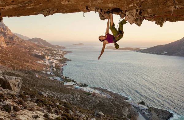 Mladá žena lezení v jeskyni při západu slunce — Stock fotografie