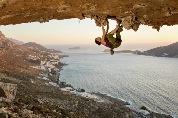 Young woman climbing in cave at sunset — Stock Photo, Image