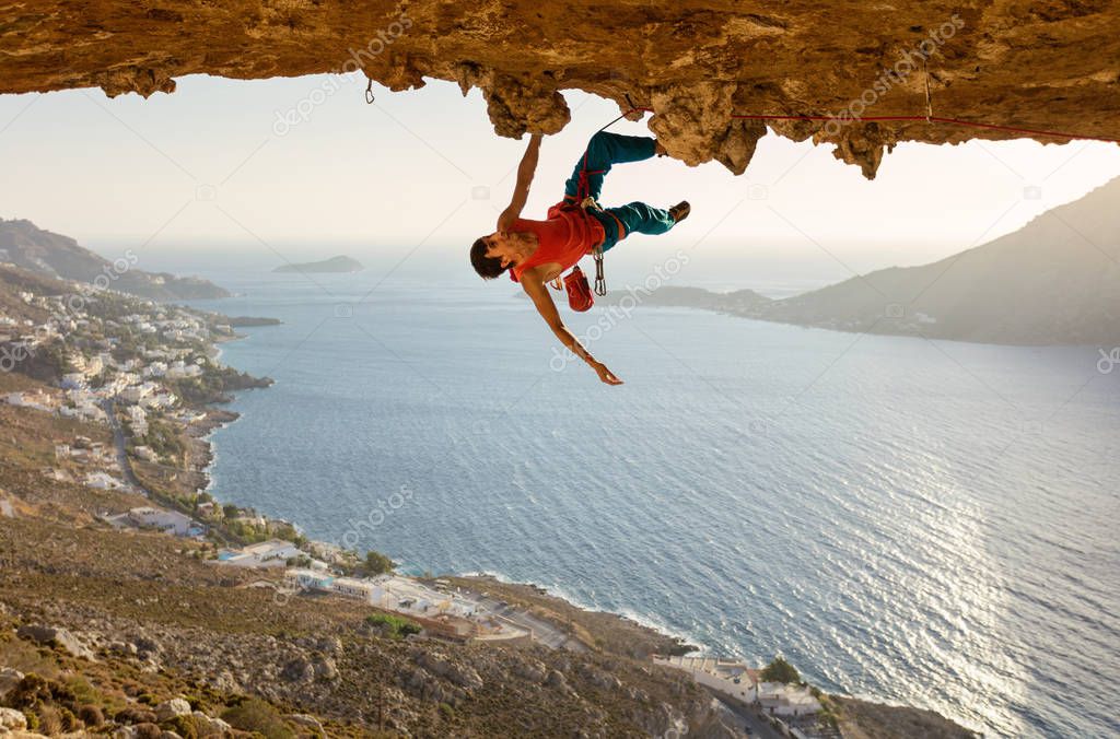 Male rock climber on challenging route going along ceiling in cave