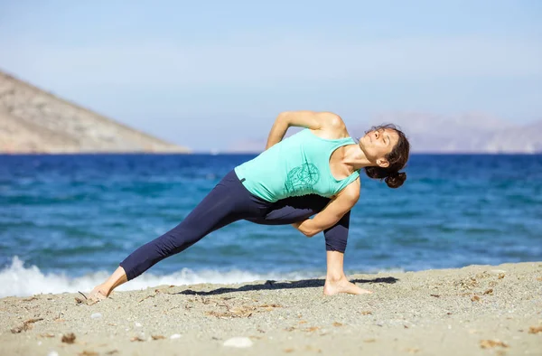 Junge Frau praktiziert Yoga am Strand — Stockfoto