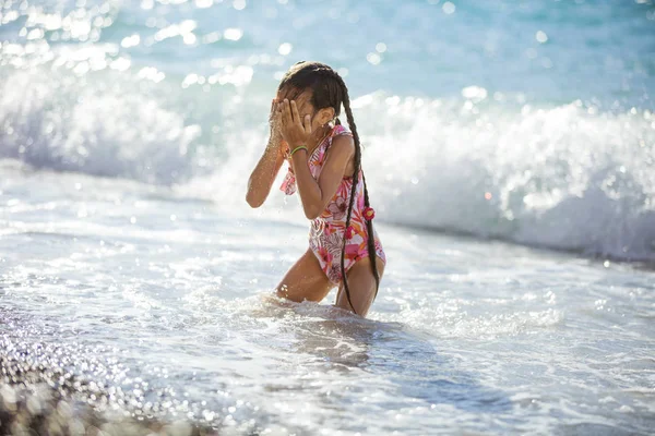 Young girl playing on beach in breaking waves and drying her fac — Stock Photo, Image