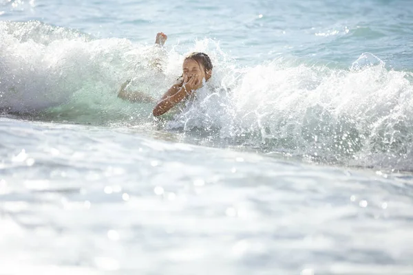 Chica joven jugando en romper las olas en la playa — Foto de Stock
