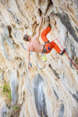 Genç adam tırmanış uçurumun üzerinde zorlu rota tırmanma