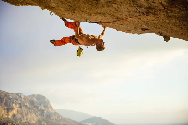 Joven escalando en repisa en cueva antes del atardecer — Foto de Stock