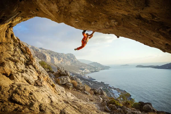 Jovem escalando rota desafiadora em caverna contra vista de cacau — Fotografia de Stock