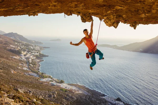 Rock climber hanging on cliff with one hand and showing thumb up — Stock Photo, Image