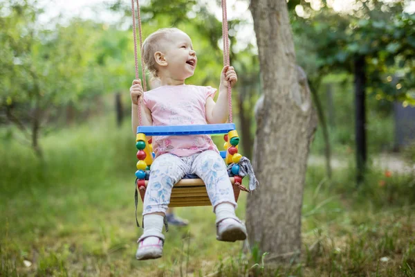 Gelukkig klein meisje op schommel in zomertuin — Stockfoto