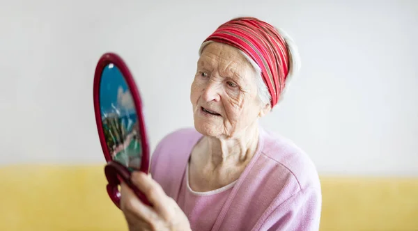 Senior mulher olhando para si mesma no espelho — Fotografia de Stock