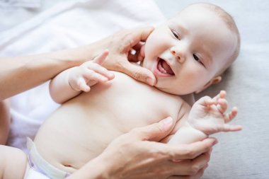 Annem ilk dişlerine bakarken neşeli, tatlı bir kız bebek yatakta yatıyor.