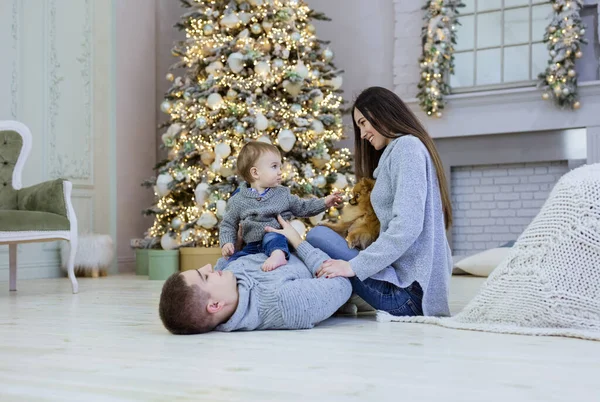 幸せな若いカップルと彼らの赤ちゃん遊び近くクリスマスツリーで家 — ストック写真