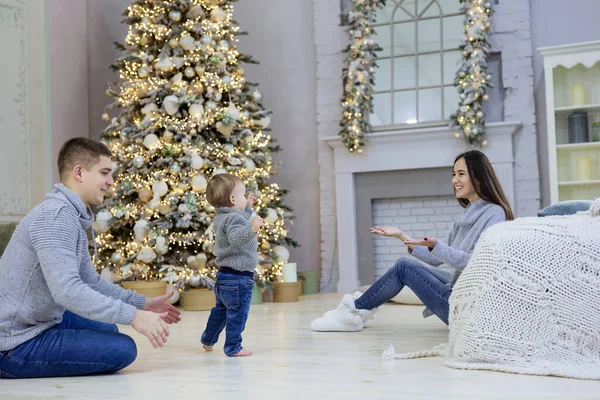 幸せな若い夫婦と自宅でクリスマスツリーの近くに彼らの赤ちゃんの息子 少年が第一歩を踏み出す — ストック写真