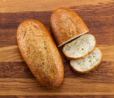 Bir somun kepekli ekmek ve ahşap arka planda dilimler.