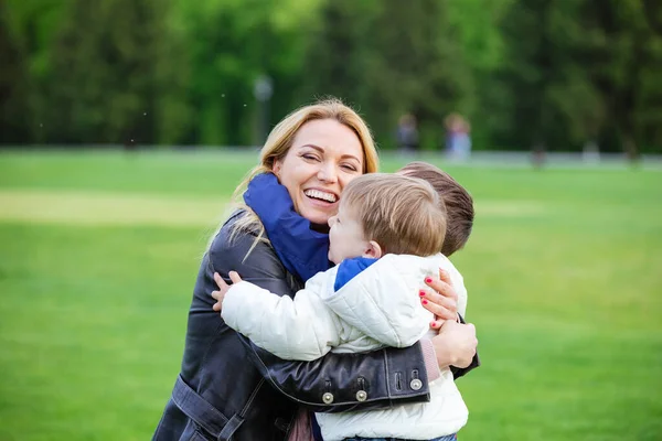 Joyeux Jeune Femme Étreignant Deux Fils Riant Dans Parc — Photo