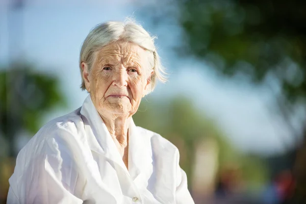 Starší Žena Sedí Lavičce Parku Dívá Kamery — Stock fotografie