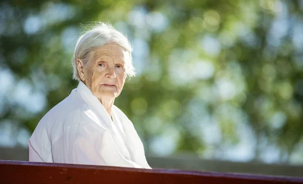 Senior Mulher Sentada Banco Parque Olhando Para Câmera — Fotografia de Stock
