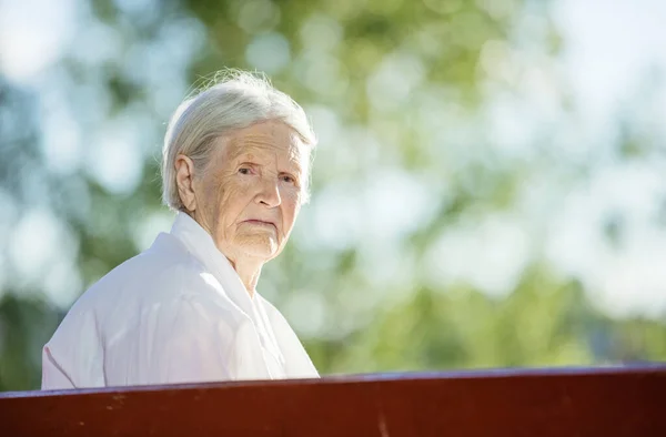 一位老妇人坐在公园的长椅上 — 图库照片