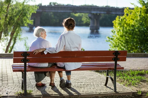 Starsza Kobieta Jej Dorosła Wnuczka Siedzą Ławce Letnim Parku — Zdjęcie stockowe