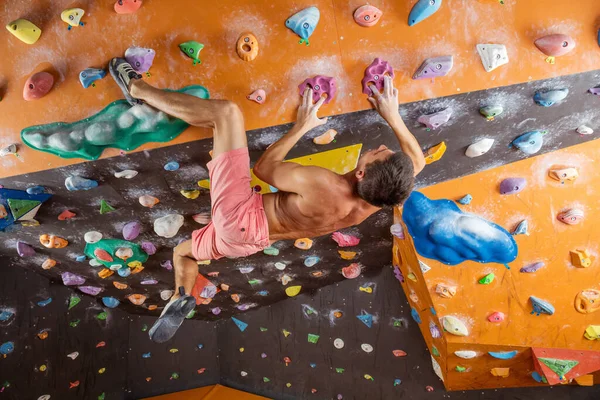 屋内クライミングジムで若い男ボルダリング 挑戦的な問題を解決しようとしている — ストック写真