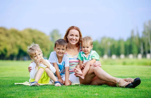 迷人的年轻女子和小儿子坐在公园的草地上 快乐的家庭享受着夏日的灿烂 父母与子女关系 — 图库照片