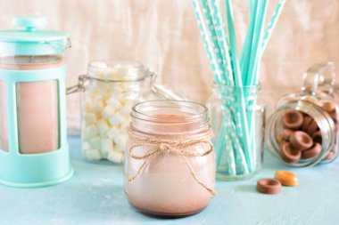 Kakao bir kavanoza. Arka plan, Turkuaz cezve, şekerleme ve kokteyl tüplerde mavi bir bulanıklık. Bir güzel nazik natürmort.