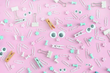 Dağınık ileti örneği ile sıradışı bir parlak görüntü. Komik suratlar kukla gözleri olan. Klipleri, clothespins, pembe bir arka plan üzerinde bir karmaşa büro düğmeleri.