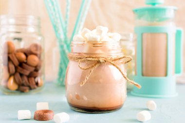 Kakao bir kablo ile bağlı bir dize bir kavanoza. Yukarıda bir kavanoza bir grup lokum gibiydi. Arka plan, Turkuaz cezve, çikolata tatlılar ve kokteyl tüplerde mavi bir bulanıklık. Nazik sakin natürmort.