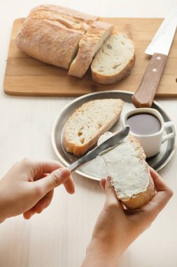 Kız ekmek üzerinde yumuşak curds yayılır. Tereyağlı taze ciabatta sandviç. Lezzetli kahvaltı kahve ile.