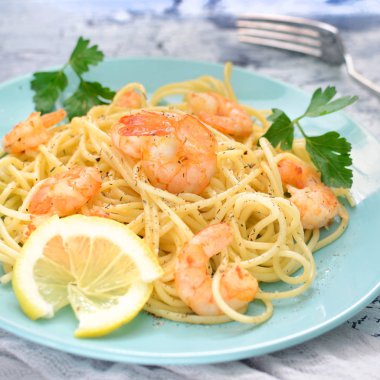 Lezzetli bir yemek, maydanoz ve limon ile dekore edilmiştir. Spagetti karides mavi plakaları. İştah açıcı yemek.