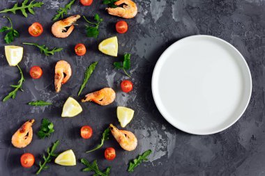 Karanlık dokulu bir arka plan üzerinde boş bir gri levha vardır. Dağınık ürünleri kenarından. Karides, limon ve Yeşiller. Yukarı alay, metin için boşluk. Düşük bir anahtar içinde güzel fotoğraf.