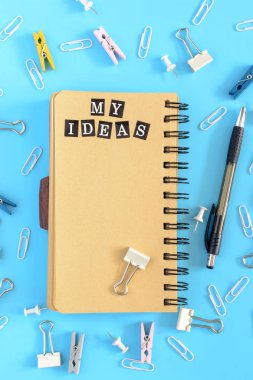 Benim fikir. Kahverengimsi sayfalarla yaylar üzerinde not defteri açın. Ofis, banka donatımı bozukluk mavi bir arka plan üzerinde dağınık vardır. Sayfanın kenarına dekoratif pembe kalp.